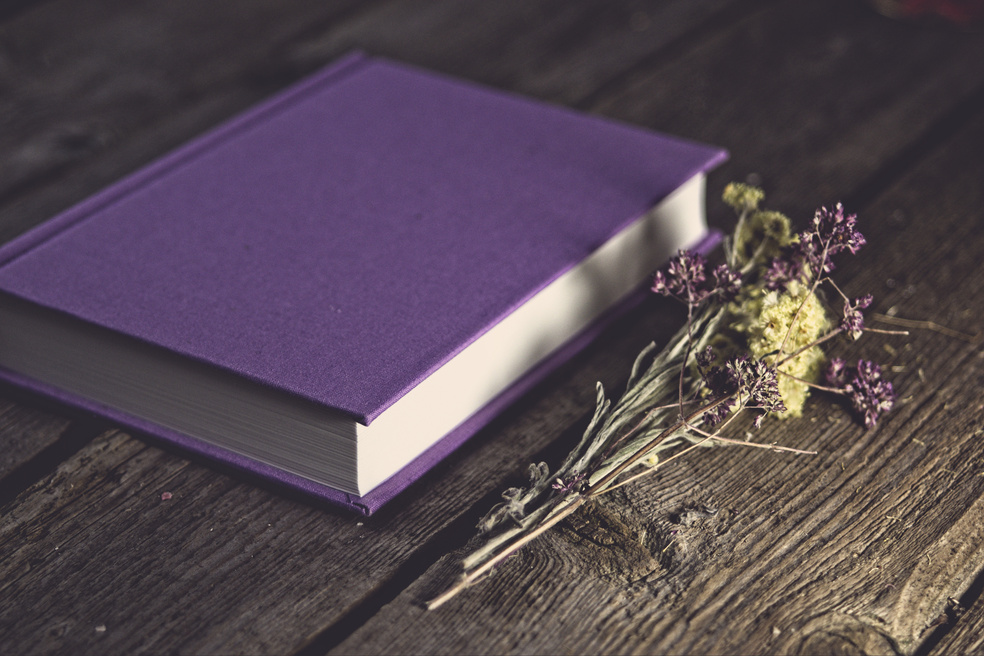 Close-Up Shot of a Purple Book on a Wooden Table